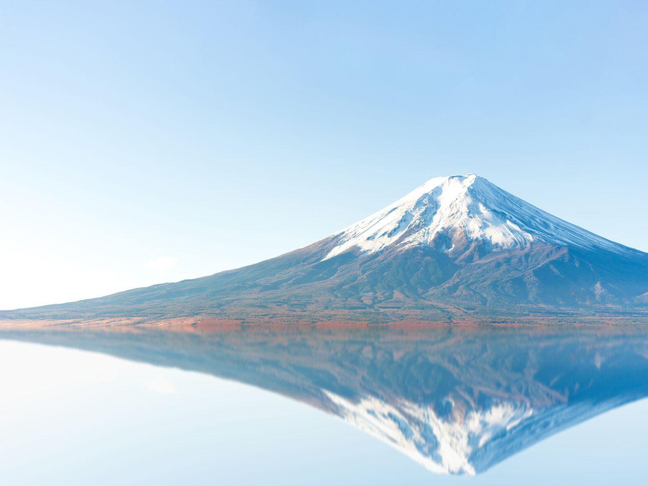 Ein schneebedeckter Berg spiegelt sich im ruhigen Wasser eines Sees. Eine ruhige Landschaft, die an die Schönheit und die Höhe Kilimandscharo erinnert.