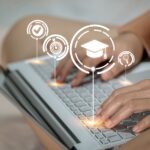 Eine Frau tippt auf einem Laptop mit einer Abschlusskappe auf dem Bildschirm